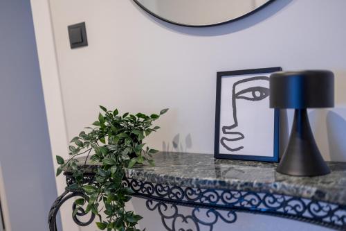 a table with a picture and a lamp and a plant at Kaleo Chios Luxury Apartments in Chios