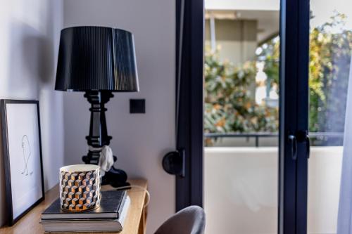 a table with a lamp and a cup on it at Kaleo Chios Luxury Apartments in Chios