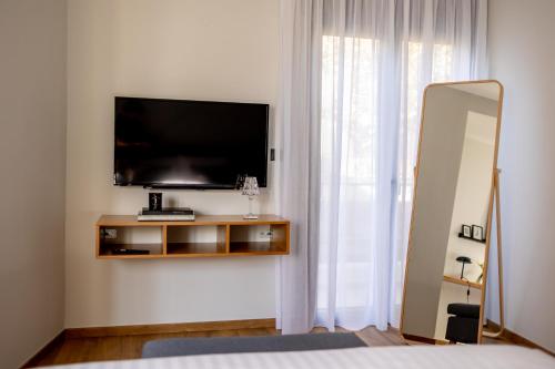 a bedroom with a television on a wall with a mirror at Kaleo Chios Luxury Apartments in Chios