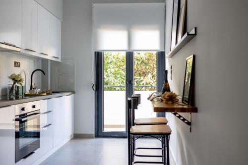 a kitchen with white cabinets and a table and a window at Kaleo Chios Luxury Apartments in Chios