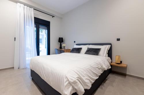 a bedroom with a large white bed and a window at Kaleo Chios Luxury Apartments in Chios