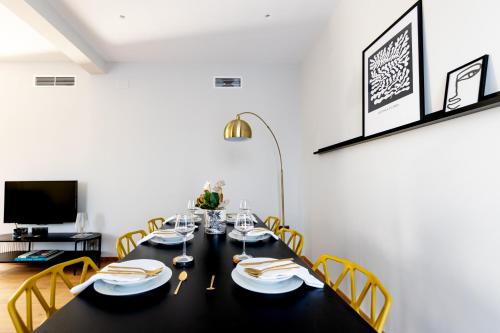 a dining room with a black table and yellow chairs at Kaleo Chios Luxury Apartments in Chios