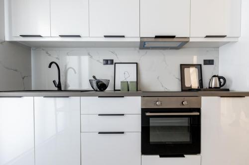 a kitchen with white cabinets and a black oven at Kaleo Chios Luxury Apartments in Chios