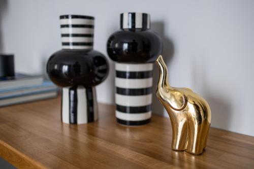two black and white vases and a gold statue on a table at Kaleo Chios Luxury Apartments in Chios