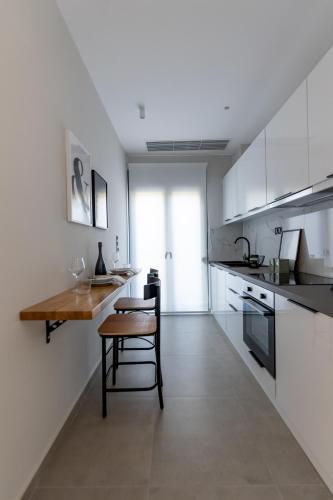 a kitchen with white cabinets and a wooden table at Kaleo Chios Luxury Apartments in Chios