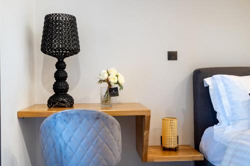 a bedside table with a blue chair and a lamp at Kaleo Chios Luxury Apartments in Chios