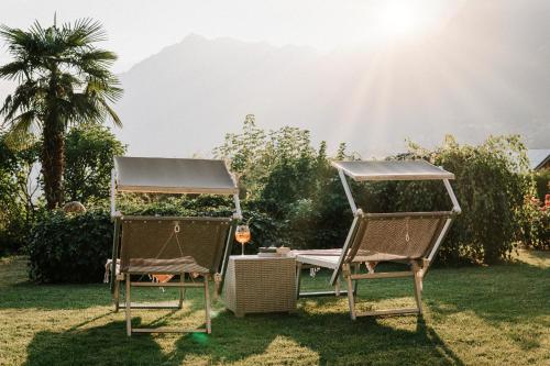 two chairs sitting in the grass with the sun behind them at Hotel Garni Katnau in Schenna