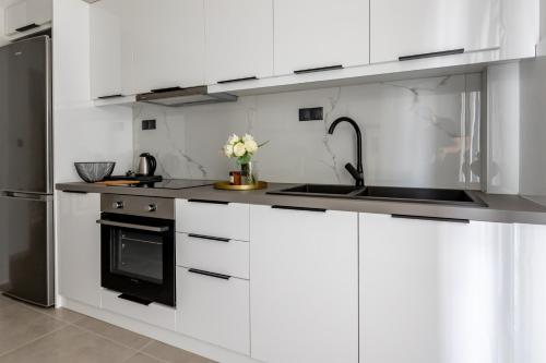 a kitchen with white cabinets and a sink and a refrigerator at Kaleo Chios Luxury Apartments in Chios