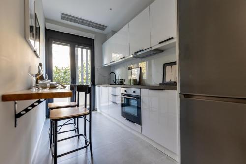 a kitchen with white cabinets and a stainless steel refrigerator at Kaleo Chios Luxury Apartments in Chios
