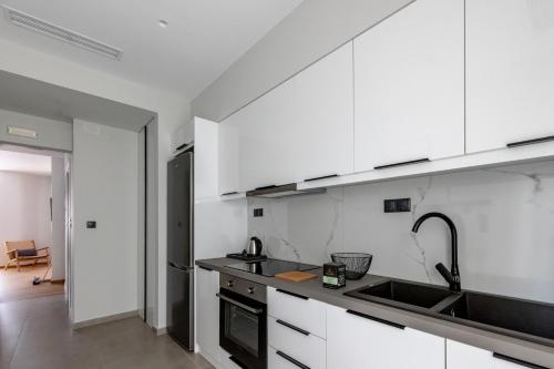a kitchen with white cabinets and a sink at Kaleo Chios Luxury Apartments in Chios