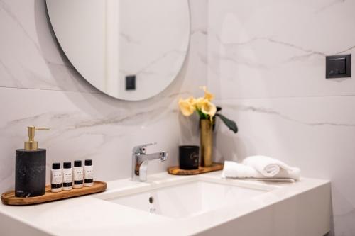 a white bathroom with a sink and a mirror at Kaleo Chios Luxury Apartments in Chios