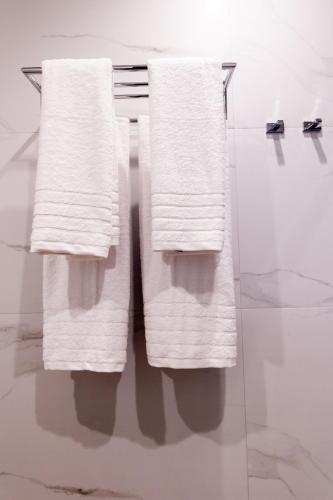 three towels hanging on a towel rack in a bathroom at Kaleo Chios Luxury Apartments in Chios