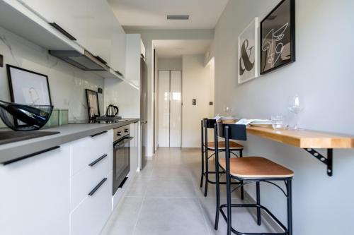 a kitchen with white cabinets and bar stools at Kaleo Chios Luxury Apartments in Chios