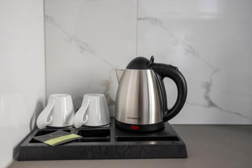 a coffee pot on a tray with two white cups at Kaleo Chios Luxury Apartments in Chios