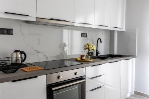 a white kitchen with white cabinets and a sink at Kaleo Chios Luxury Apartments in Chios