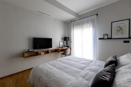 a white bedroom with a bed and a television at Kaleo Chios Luxury Apartments in Chios
