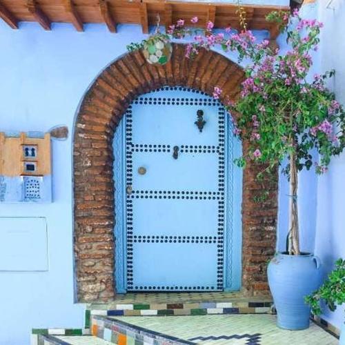 an archway with a blue door and a vase of flowers at Casa Plasa Grande in Chefchaouene