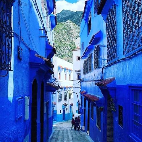 a group of people walking down a street with blue buildings at Casa Plasa Grande in Chefchaouene