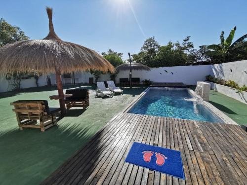 a pool with a straw umbrella and chairs and a table at Casa mono ambiente y piscina. in Limpio