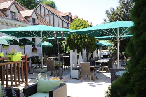 a patio with tables and chairs and umbrellas at Logis Le Bourguignon in Bèze