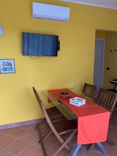 a dining room table with chairs and a tv on a yellow wall at Villa Melissa in Diano Castello