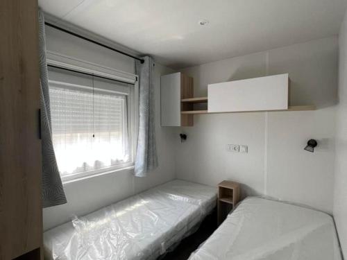 a small bedroom with two beds and a window at Superbe Mobil home 6-8 personnes (57) in Saint-Jean-de-Monts