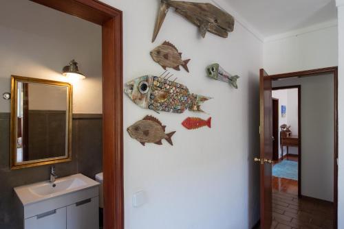 Baño con adornos de pescado en la pared en Moby Dick Lodge, en Malveira da Serra