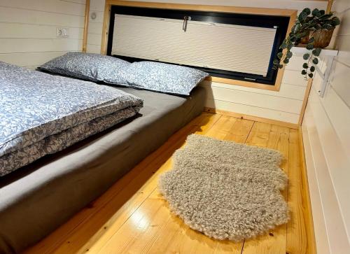a bedroom with a bed with a rug and a window at Tiny house with garden and jacuzzi near Amsterdam in Vijfhuizen
