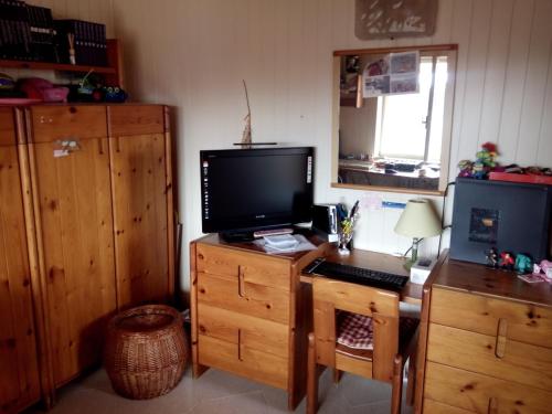 a room with a desk with a television on a wooden cabinet at Appartamento Ognina Siracusa in Ognina