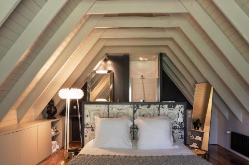 1 dormitorio en el ático con 1 cama con almohadas blancas en Le Pavillon de Kériolet, en Concarneau