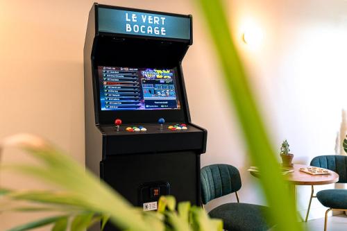 Logis Hôtel & Restaurant Le Vert Bocage في Franqueville-Saint-Pierre: وجود آلة ألعاب فيديو في غرفة مع كراسي