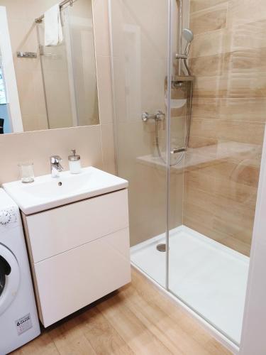 a bathroom with a shower and a sink and a washing machine at SEA & YOU Apartament z widokiem na morze - Dwie Sosny in Ustronie Morskie