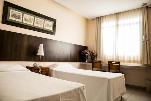 a hotel room with two beds and a window at Pousada Sossego da Pampulha in Belo Horizonte