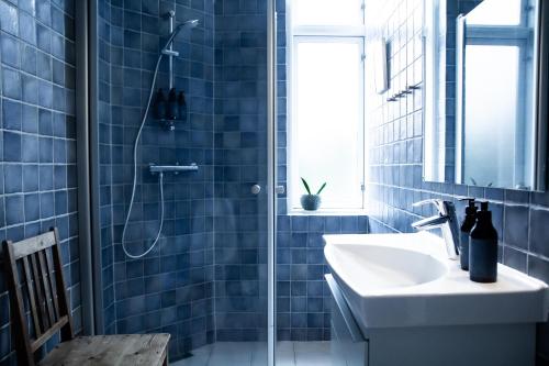 baño con lavabo y ducha con azulejos azules en Hotel Aahøj en Sæby