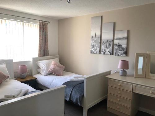 a bedroom with two beds and a dresser and a window at Comfort, peace and quiet guaranteed in this 3 bed in West Auckland