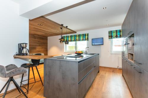 a kitchen with a stainless steel island and a table at lechner living apartments in Wald im Pinzgau