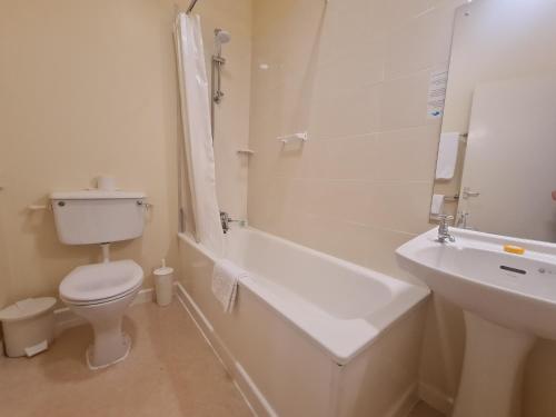 a white bathroom with a toilet and a sink at Villa Nova in Saint Helier Jersey