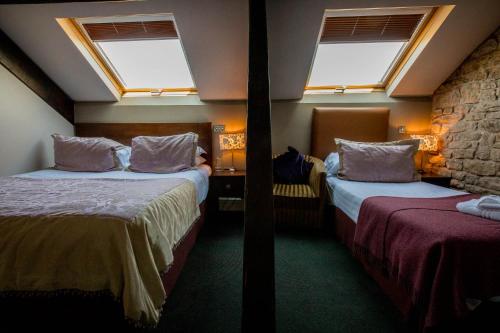two beds in a room with two windows at The Sun Hotel & Bar in Lancaster