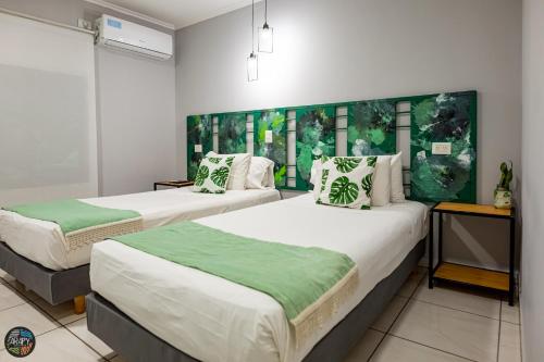 um quarto com 2 camas com almofadas verdes e brancas em Arapy Bed and Dream em Puerto Iguazú
