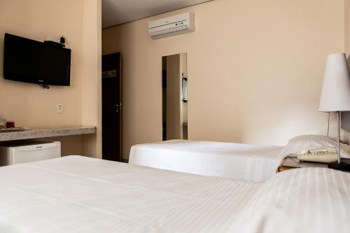 a hotel room with two beds and a flat screen tv at Pousada Sossego da Pampulha in Belo Horizonte