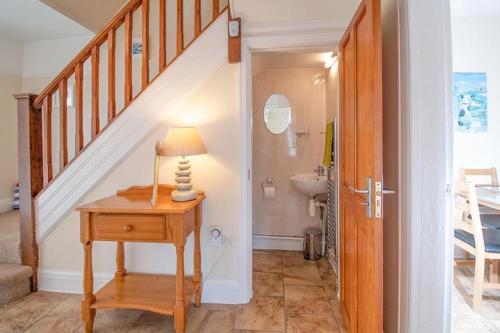 a hallway with a staircase and a table with a lamp at Anrose House in Llandrillo-yn-Rhôs