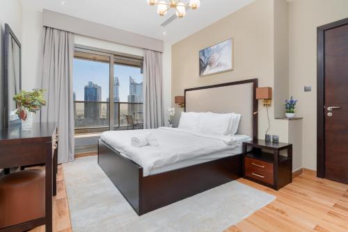 um quarto com uma cama, uma secretária e uma janela em White Sage - Elite Residence 1 bedroom em Dubai