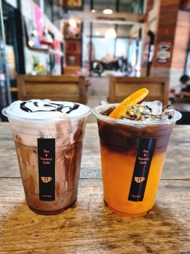 two cups of drinks sitting on a wooden table at The 8 Factory Hotel Phitsanulok in Phitsanulok