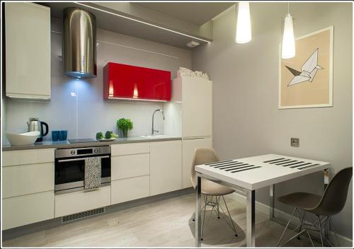 a kitchen with red cabinets and a table with chairs at InPoint Central Apartments in Kraków