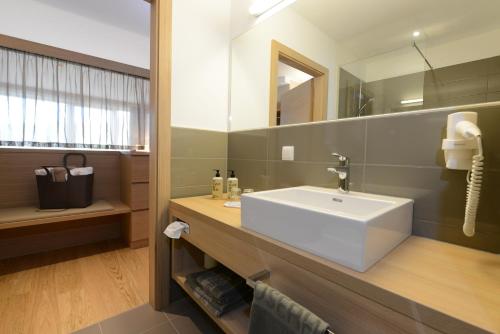 a bathroom with a white sink and a mirror at Hotel Moserhof in Seeboden