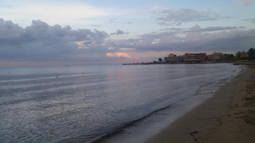 a beach with a cloudy sky and the ocean at Crystal Home near Airport in Artemida