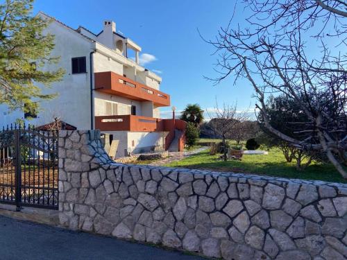 ein Haus mit einer Steinmauer und einem Zaun in der Unterkunft Family apartments TOMY in Punat
