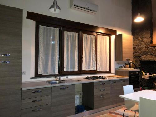 a kitchen with a sink and a stove and windows at La pietra lavica in Linguaglossa