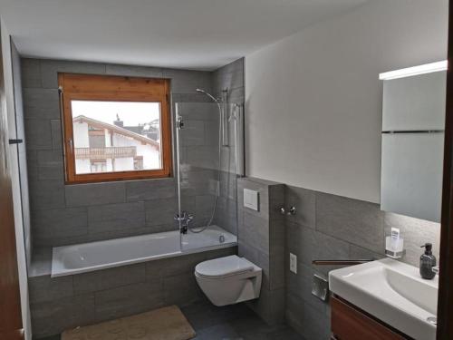 y baño con bañera, aseo y lavamanos. en Ferienwohnung im Haus Soldanella, en Obersaxen