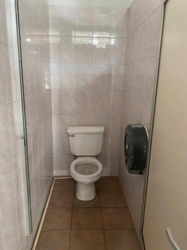 a small bathroom with a toilet and a toilet paper dispenser at Nomada Hostel Oaxaca - Vive nómada! in Oaxaca City